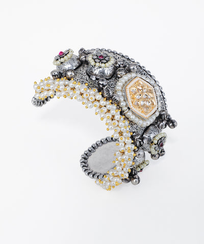 Oxidized silver-tone cuff bracelet with floral motifs, faux pearls, and clear and red stones.