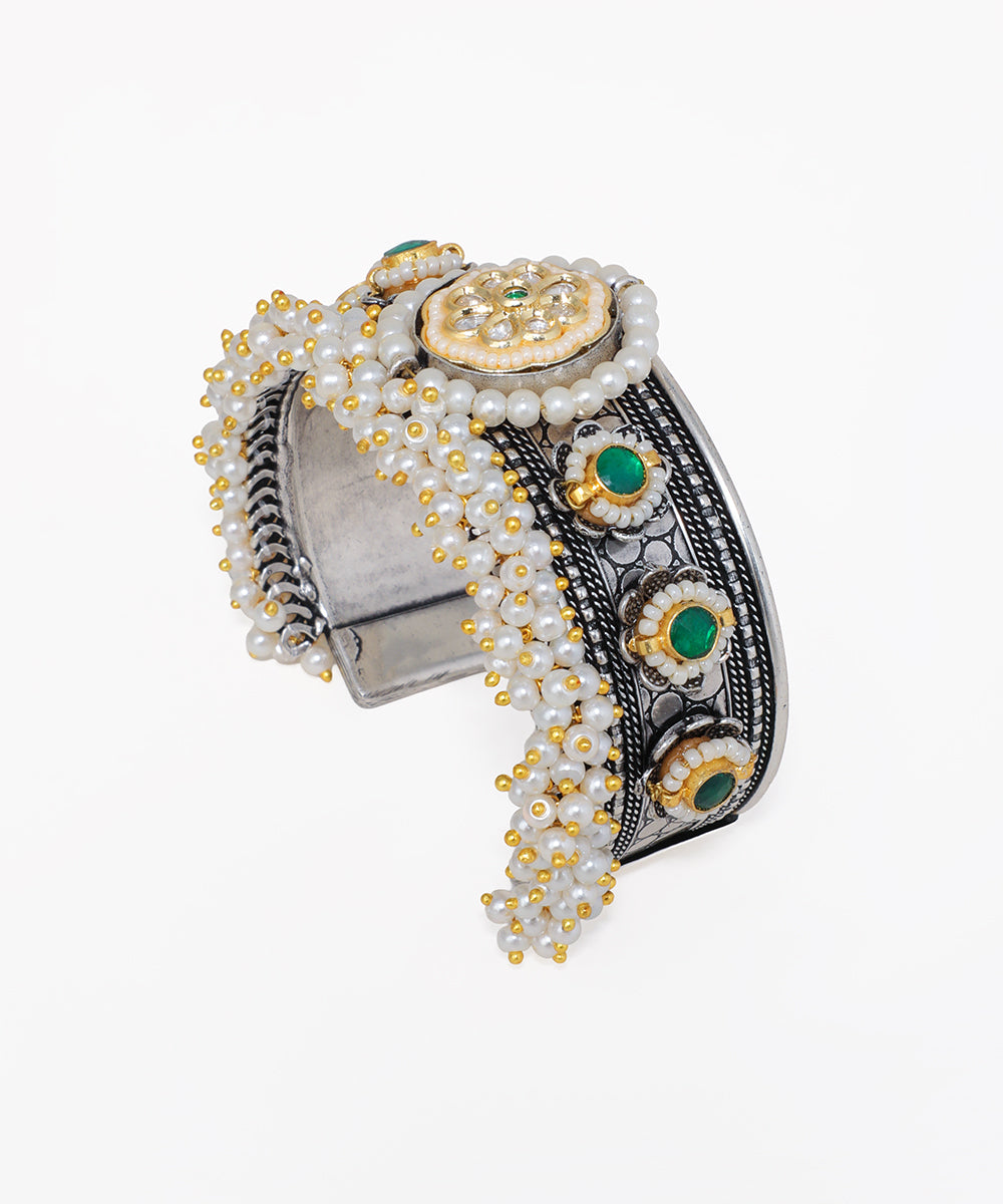 Decorative bracelet with pearls, gold accents, and green stones on a white background