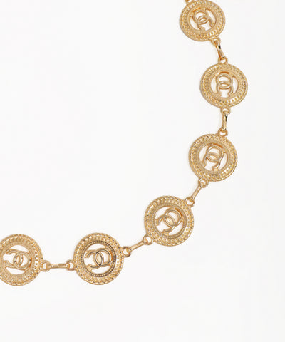Gold necklace with circular design on a white background