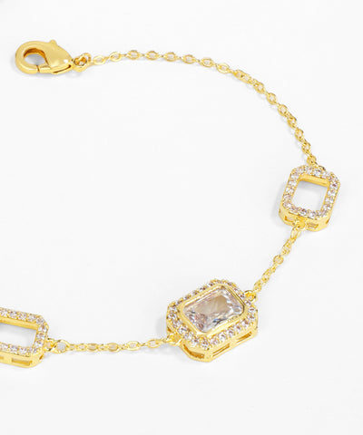 Gold bracelet with square-shaped gemstones on a white background