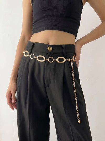 Person wearing black pants with a gold chain belt on a white background