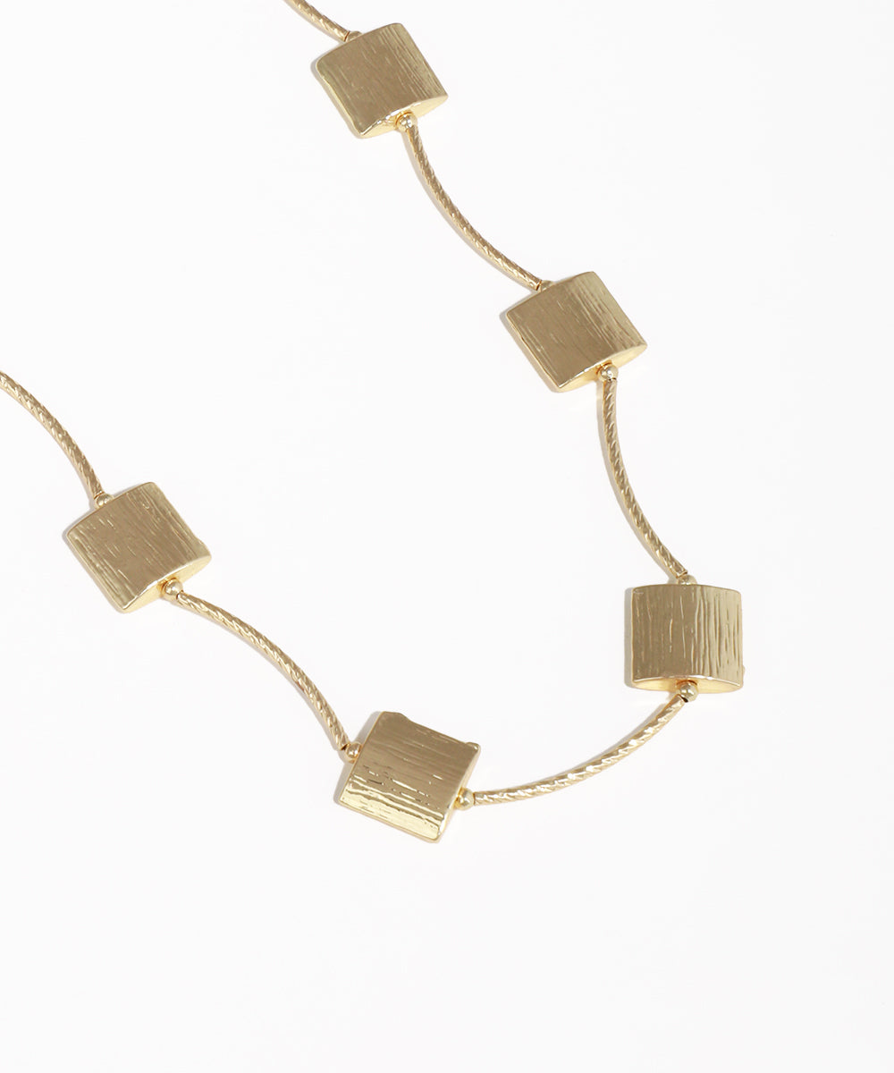 Gold necklace with square pendants on a white background