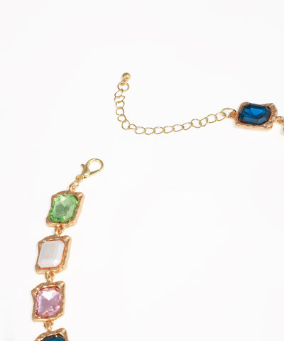 Gold bracelet with multicolored gemstones on a white background
