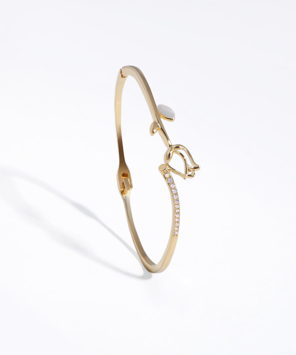 Gold-tone bracelet with sculpted tulip motif, white leaf accent, and line of clear CZ stones.