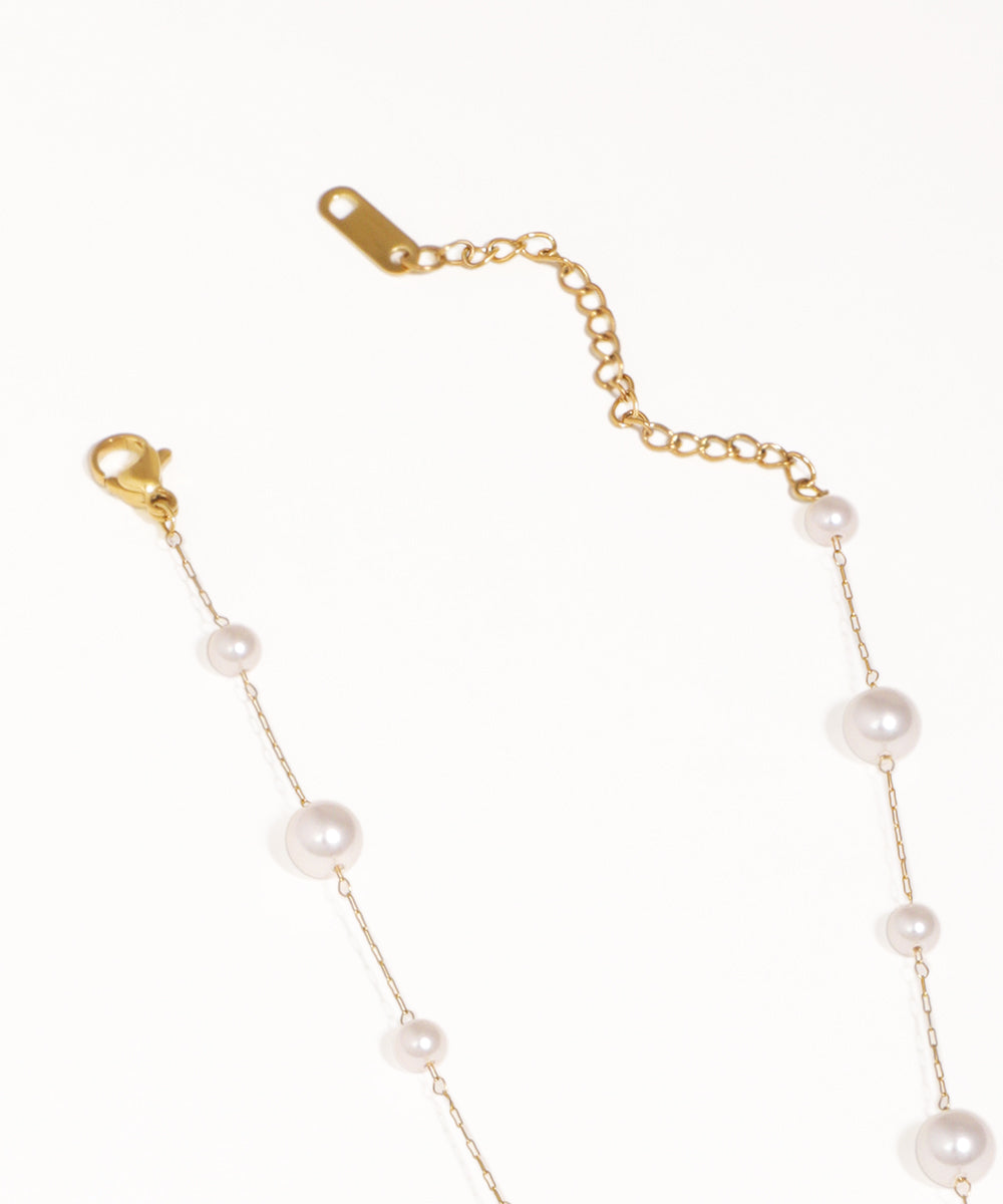 Gold chain bracelet with pearls on a white background