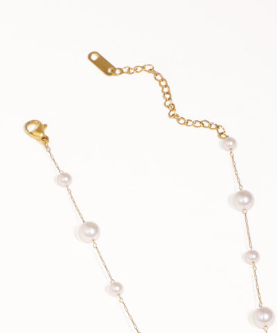 Gold chain bracelet with pearls on a white background