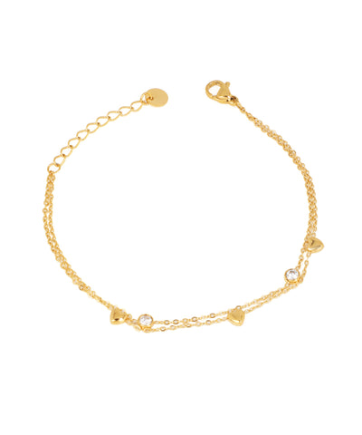 Gold-tone layered chain bracelet with small heart charms and round bezel-set clear stones, lobster clasp.
