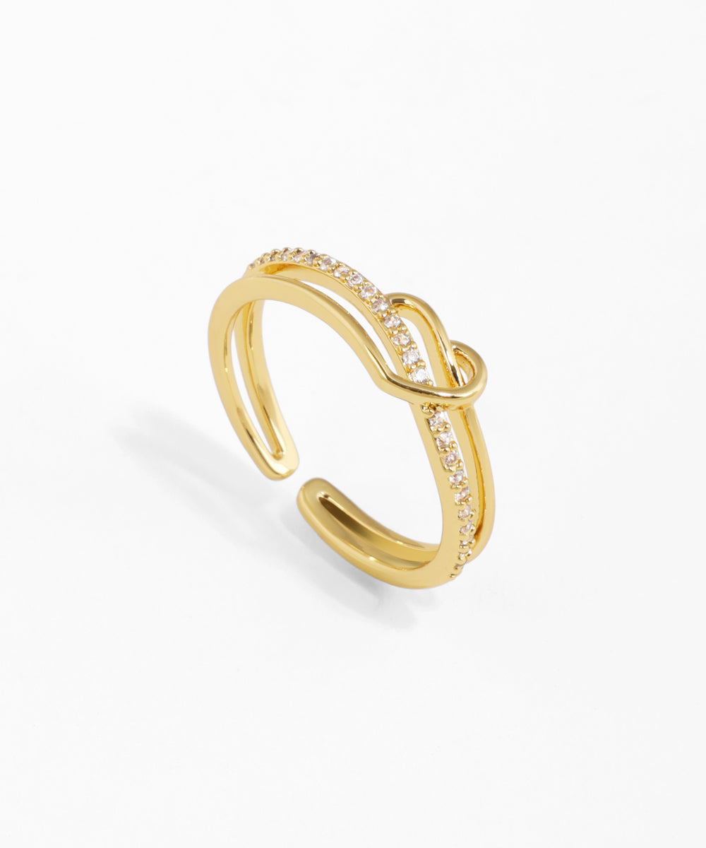 Gold-tone adjustable ring with intertwined bands, one smooth and one embellished with clear CZ stones.