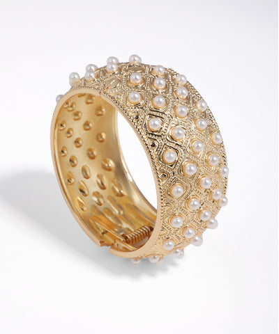 Gold-tone bangle bracelet with intricate diamond pattern and faux pearls.