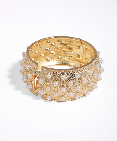 Gold bracelet with pearl accents on a white background
