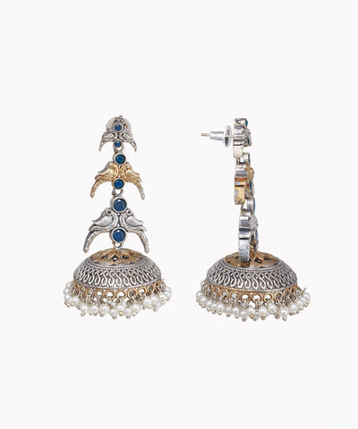 Pair of ornate earrings with blue stones and pearl-like elements on a white background