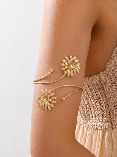 Gold floral arm band on a person's arm with a neutral background