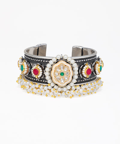Decorative bracelet with metallic and gemstone details on a white background