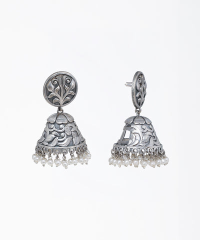 Oxidized finish jhumka earrings with intricate floral patterns and small faux pearl drops