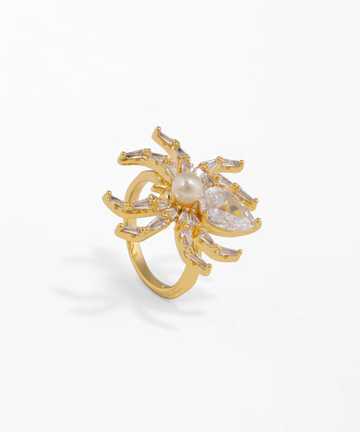 Gold ring with a central pearl and diamond-like stones on a white background