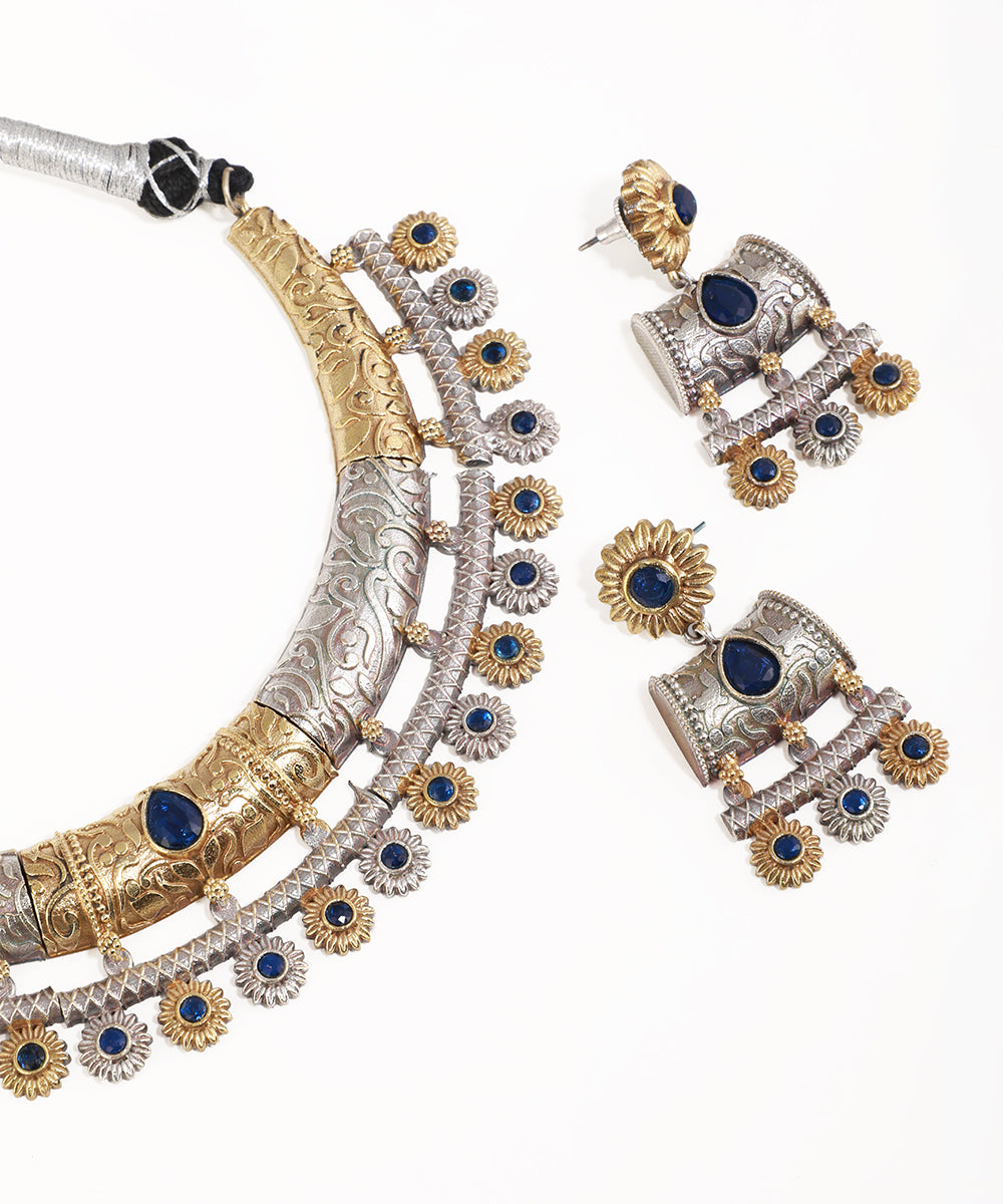 Ornate silver and gold jewelry set with blue stones on a white background