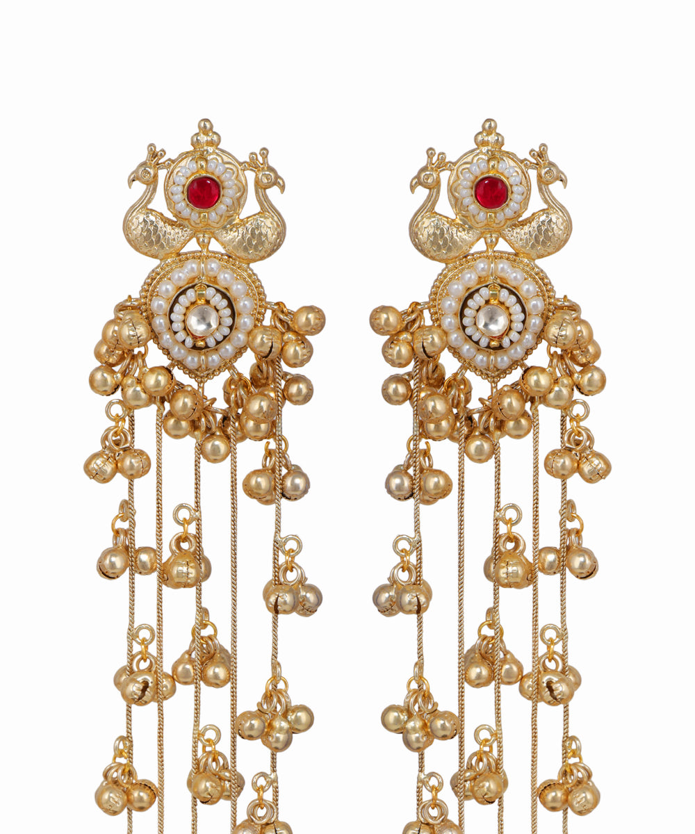 Ornate gold earrings with red gemstones on a white background