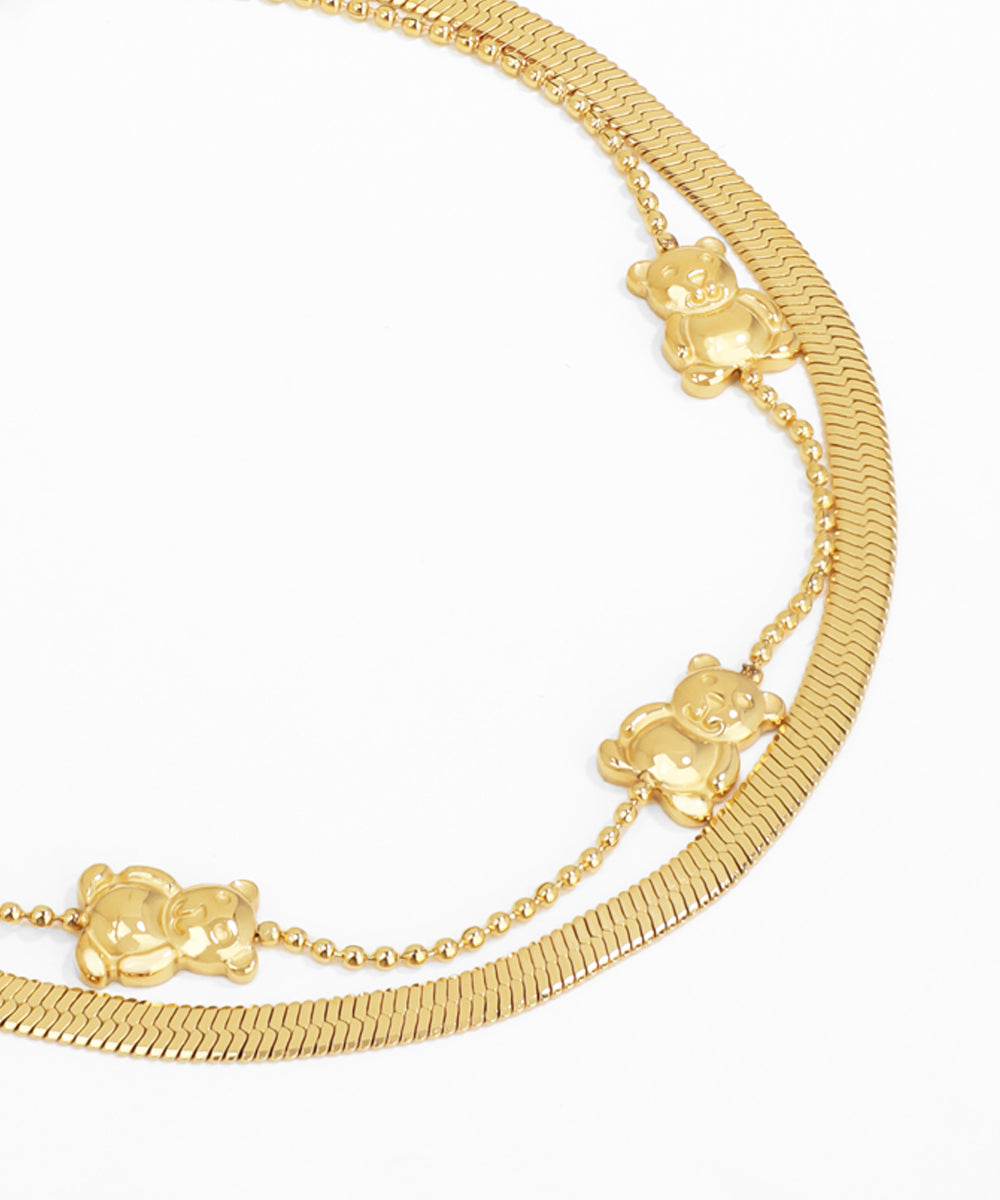 Gold bracelet with teddy bear charms on a white background