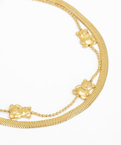 Gold bracelet with teddy bear charms on a white background