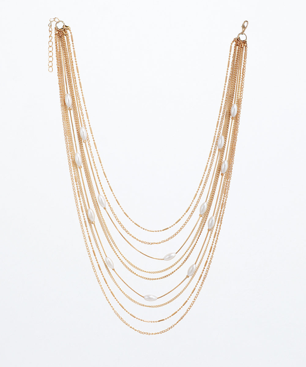 Gold-tone layered necklace with varied chains and interspersed white oval faux pearls, featuring an extender chain.