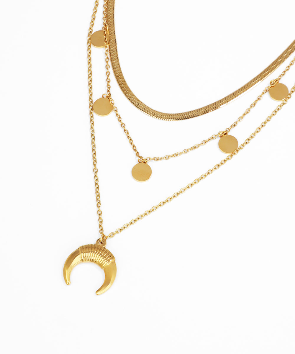 Gold layered necklace with crescent moon pendant on a white background