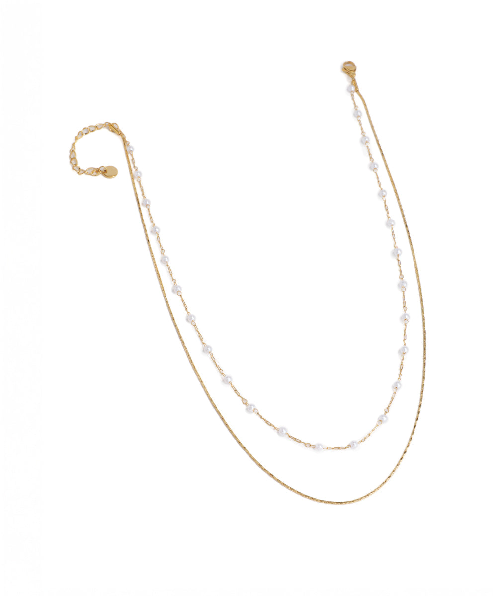 Two pearl necklaces on gold chains against a white background