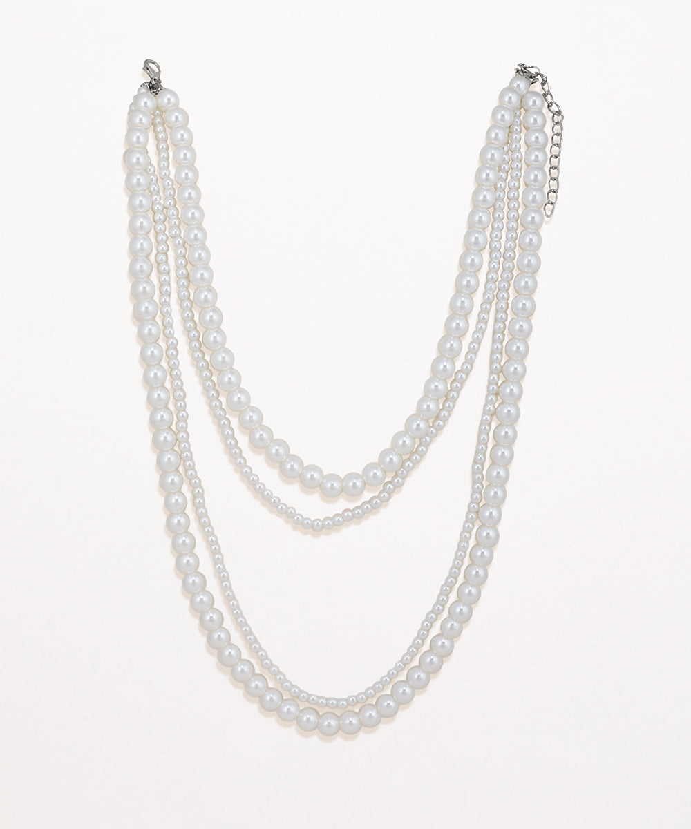 Rhodium finish multi-strand necklace with three layers of faux pearls of varying sizes.