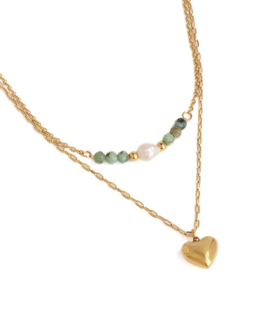 Gold necklace with heart pendant and green beads on a white background
