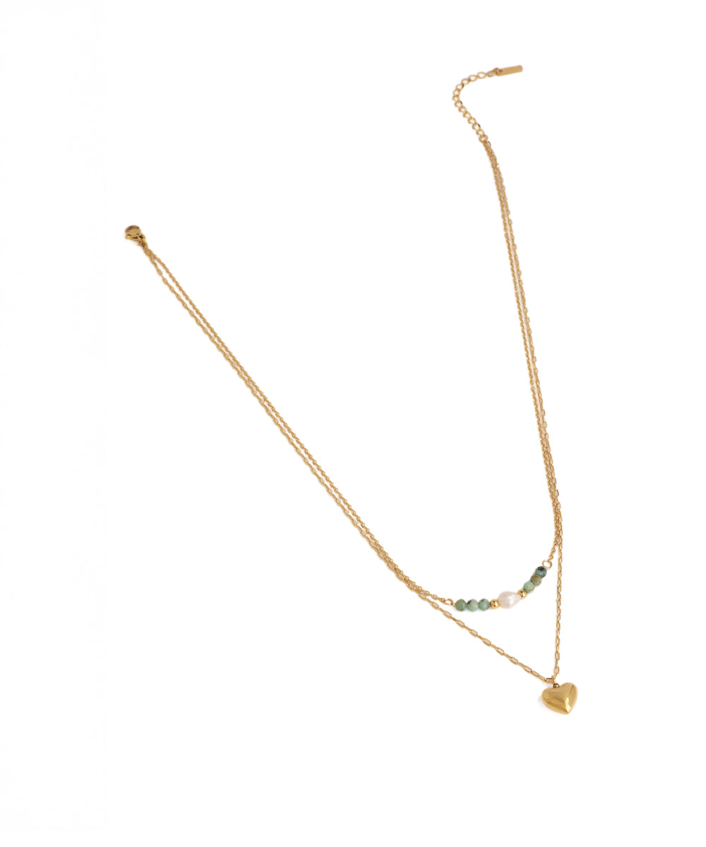Gold necklace with heart pendant on a white background