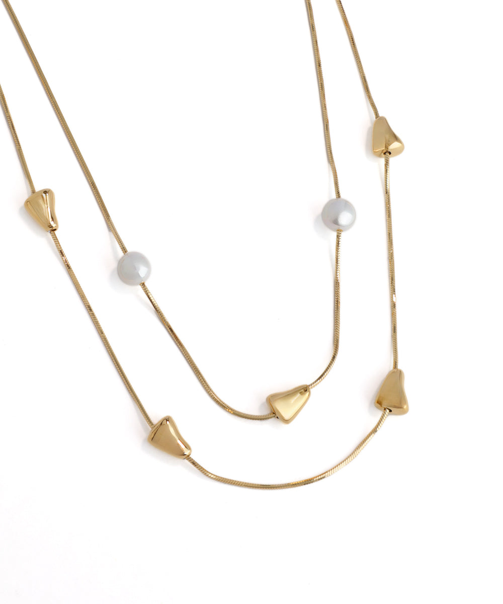 Gold necklace with pearl-like beads on a white background