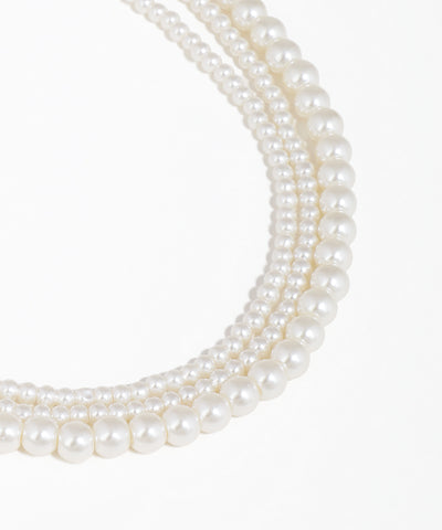 Multiple strands of pearls on a white background