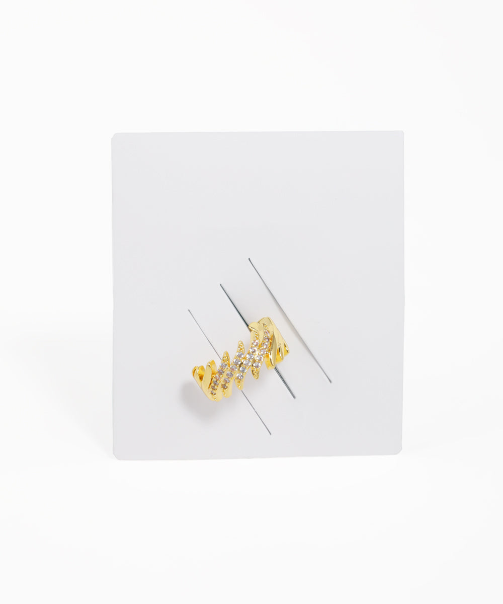 Gold earring on a white card with a white background