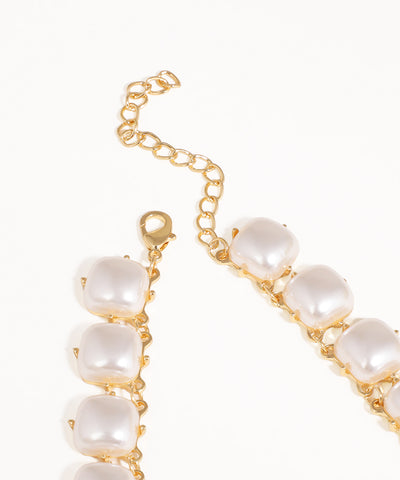 Gold bracelet with pearl-like beads on a white background