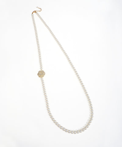 Gold-tone long beaded necklace with an off-center floral accent adorned with clear stones