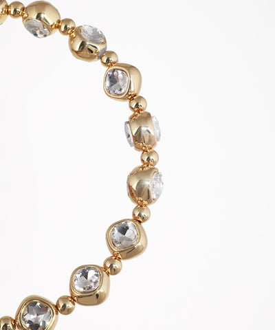 Gold bracelet with clear gemstones on a white background