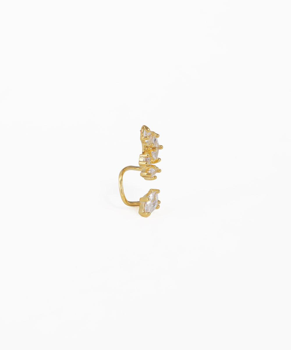 Gold ear cuff with embedded stones on a white background