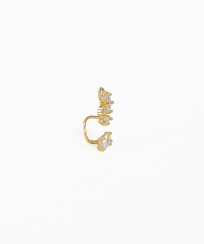 Gold ear cuff with embedded stones on a white background