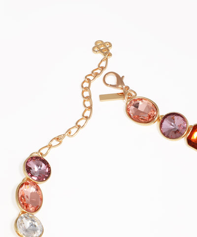 Gold bracelet with pink and clear gemstones on a white background