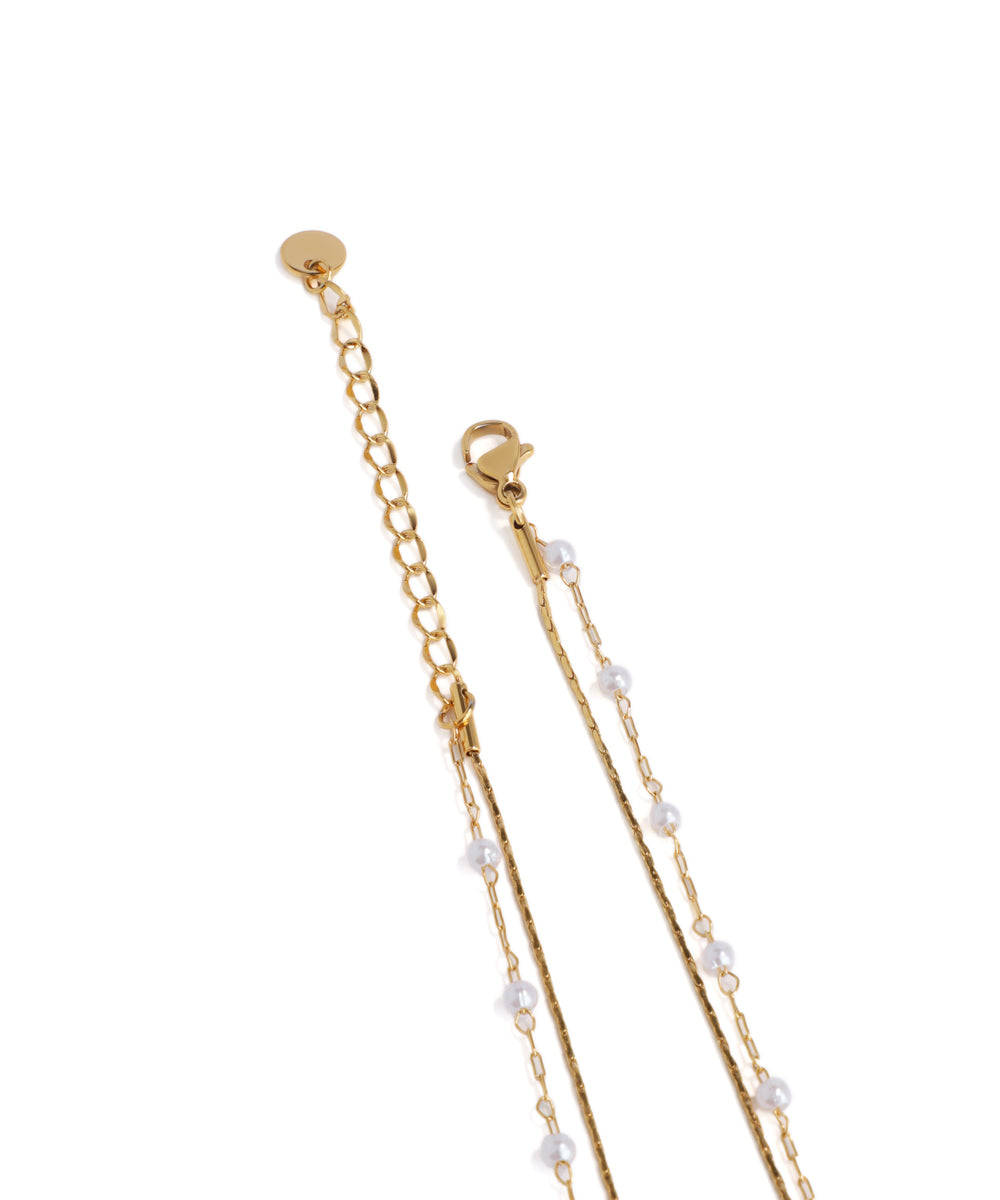 Gold necklace with pearl beads on a white background