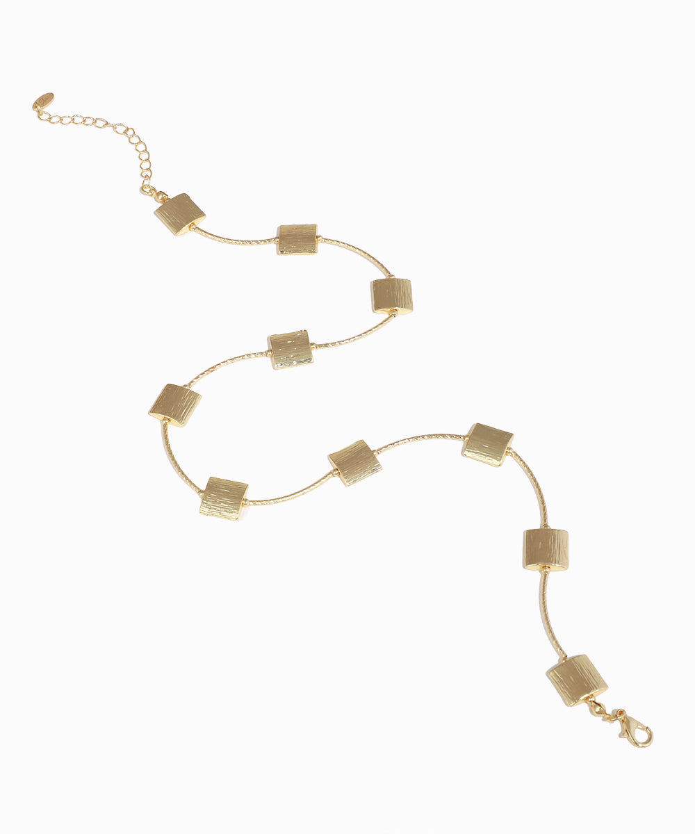 Gold necklace with square pendants on a white background