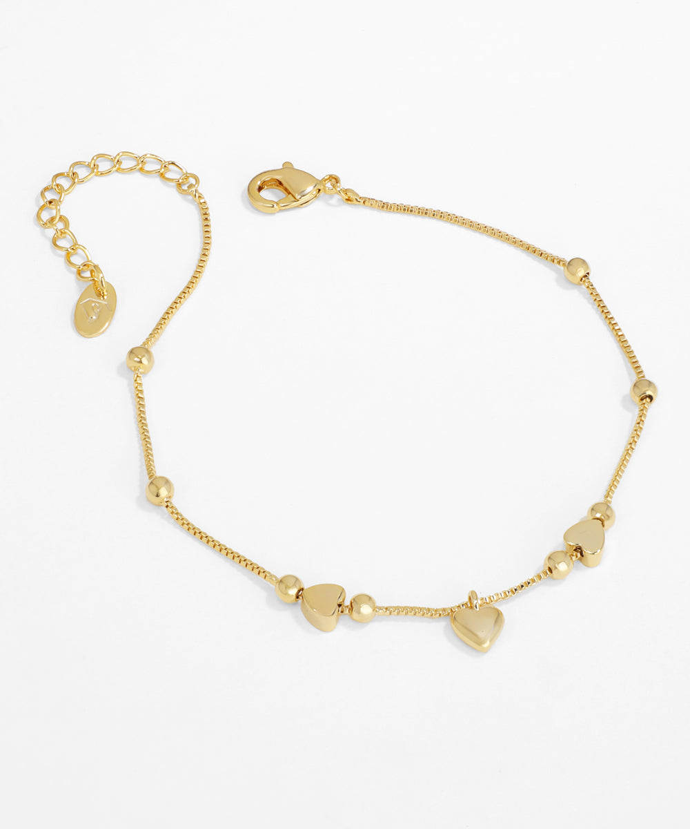 Gold bracelet with heart-shaped charms on a white background