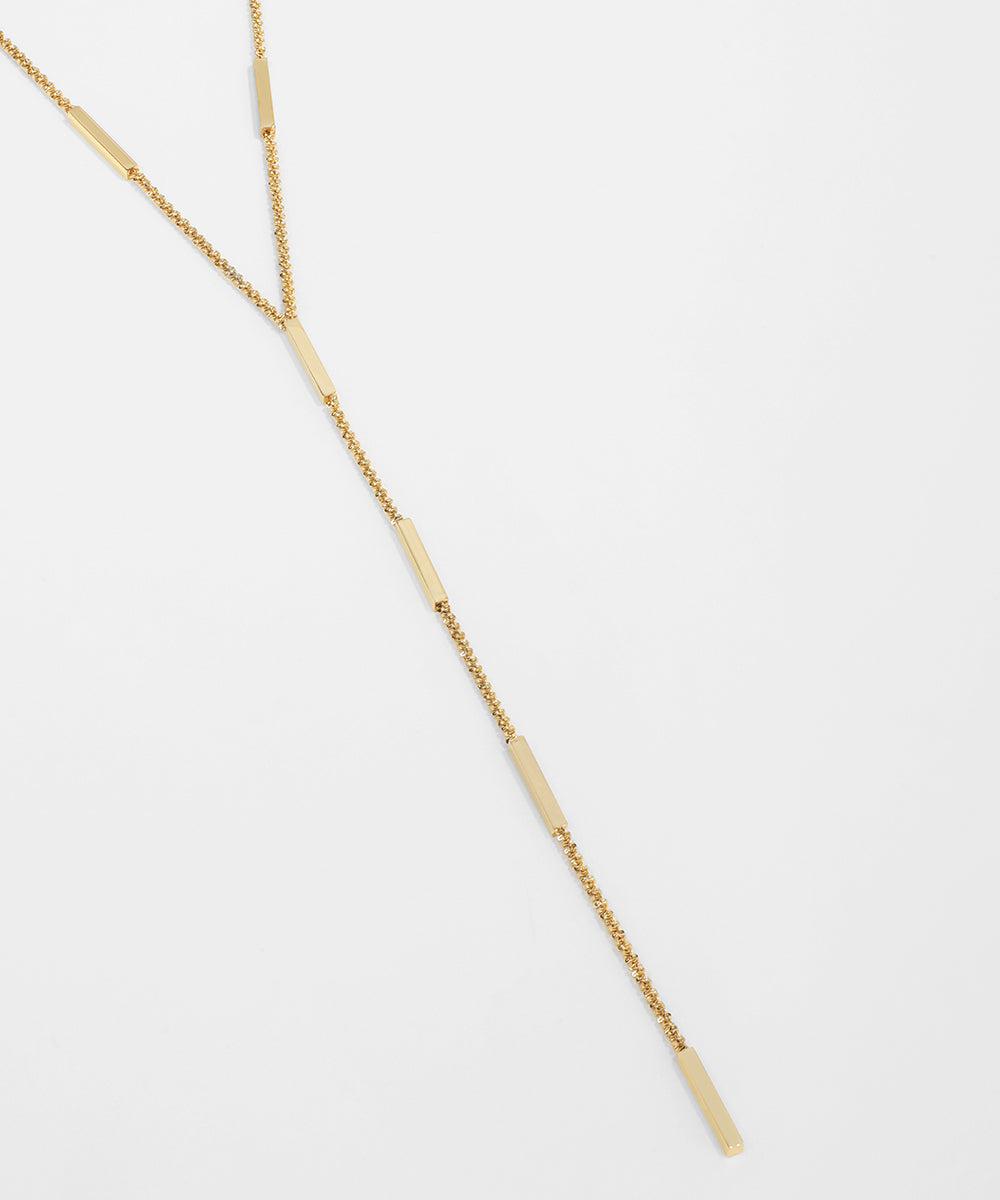 Gold necklace on a light gray background