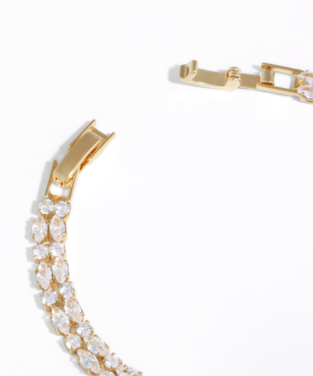 Gold bracelet with clear gemstones on a white background