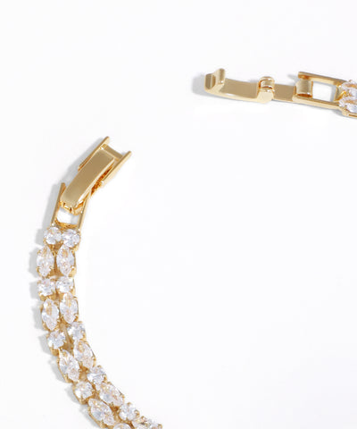 Gold bracelet with clear gemstones on a white background