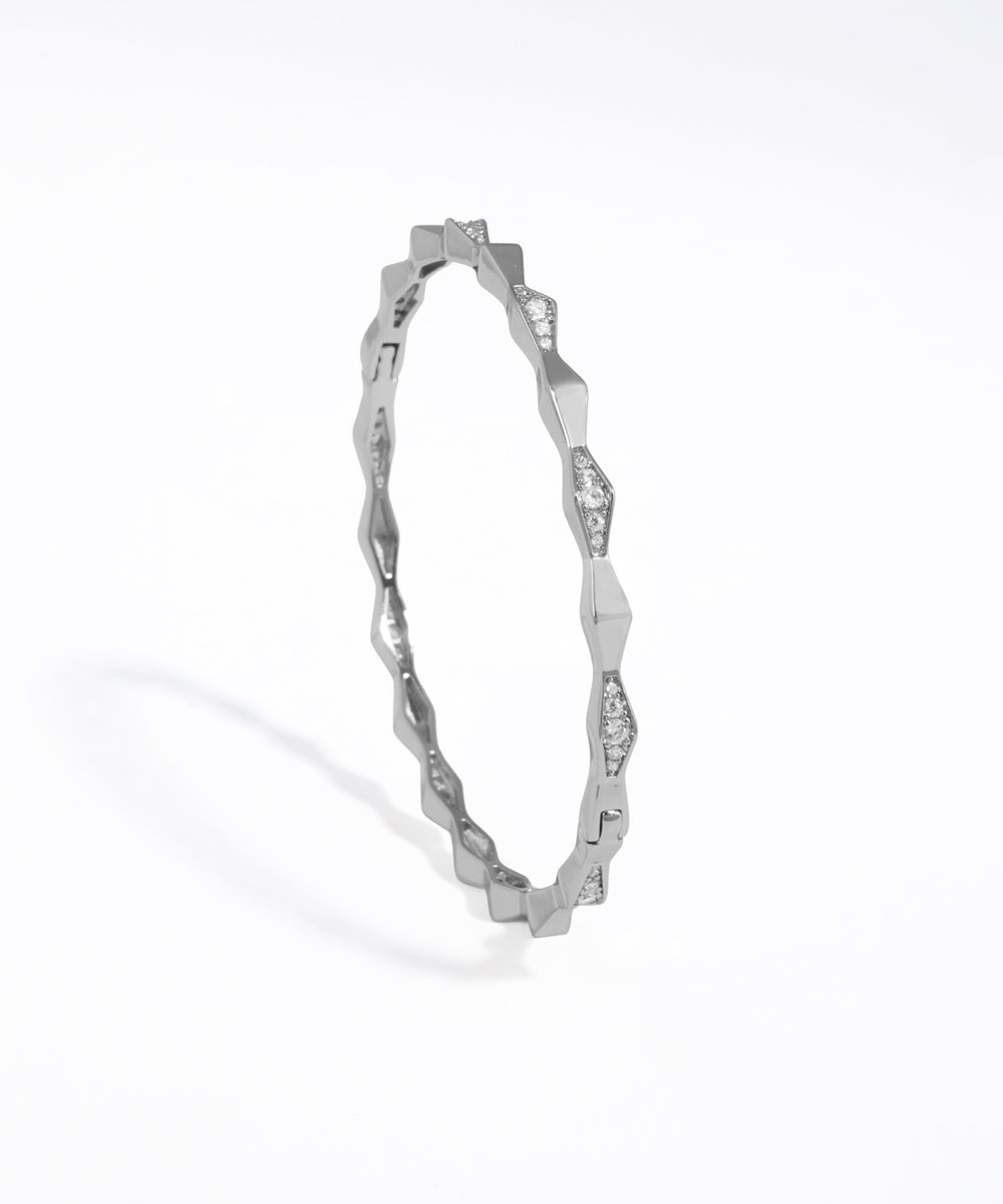 Silver ring with a wavy design on a white background