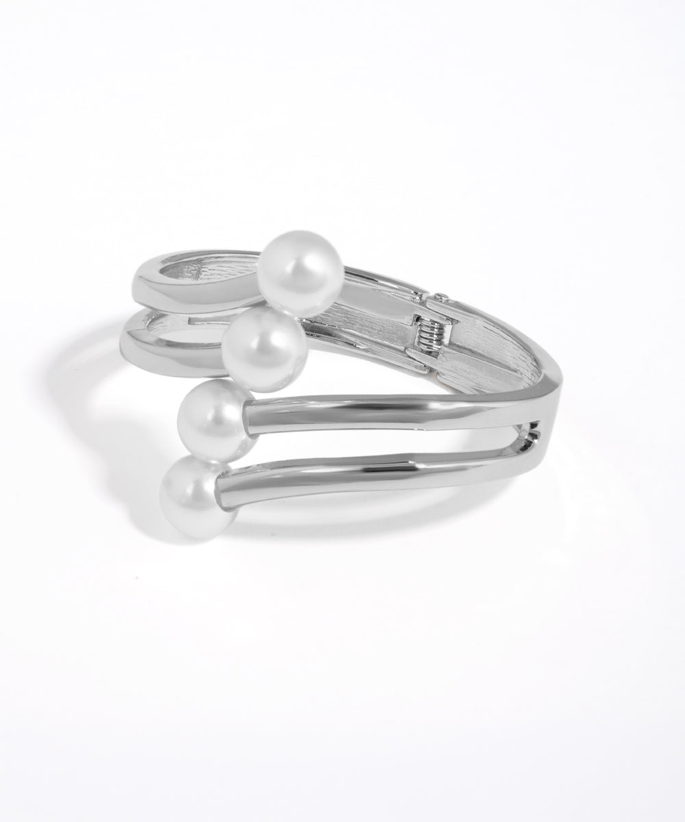 Silver bracelet with three pearls on a white background
