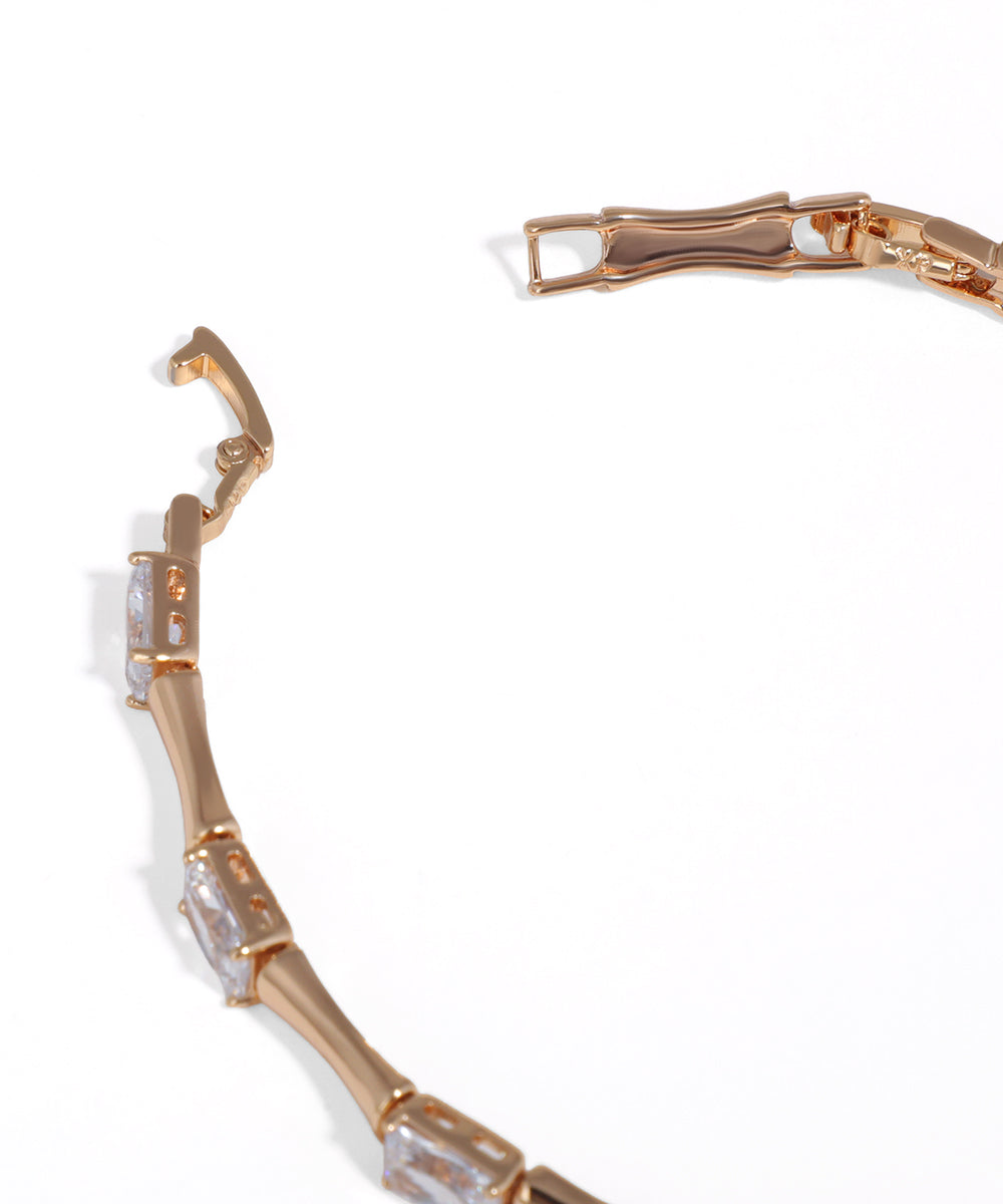 Rose gold bracelet with clear gemstones on a white background