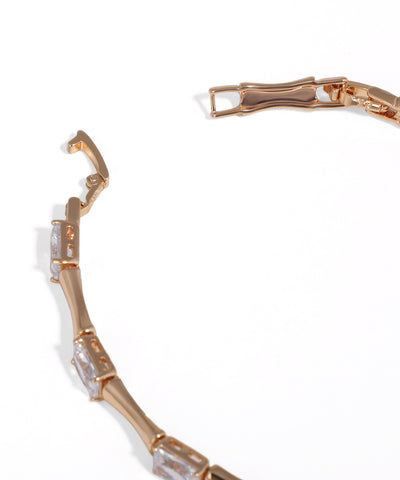 Rose gold bracelet with clear gemstones on a white background
