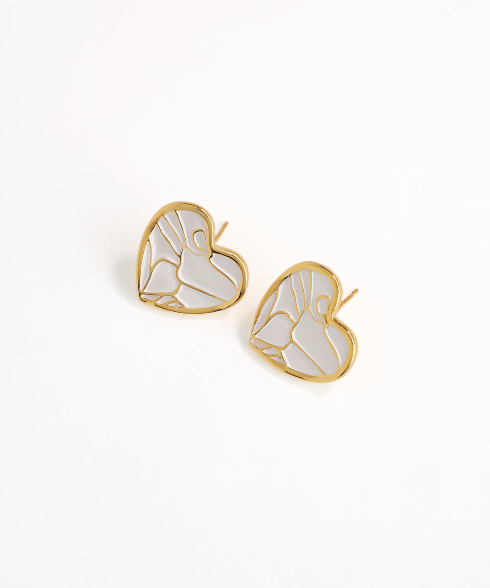 Gold and white butterfly-shaped earrings on a light beige background