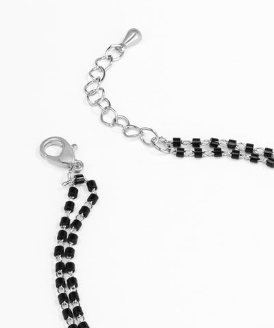 Black and white beaded bracelet with silver clasp on a white background